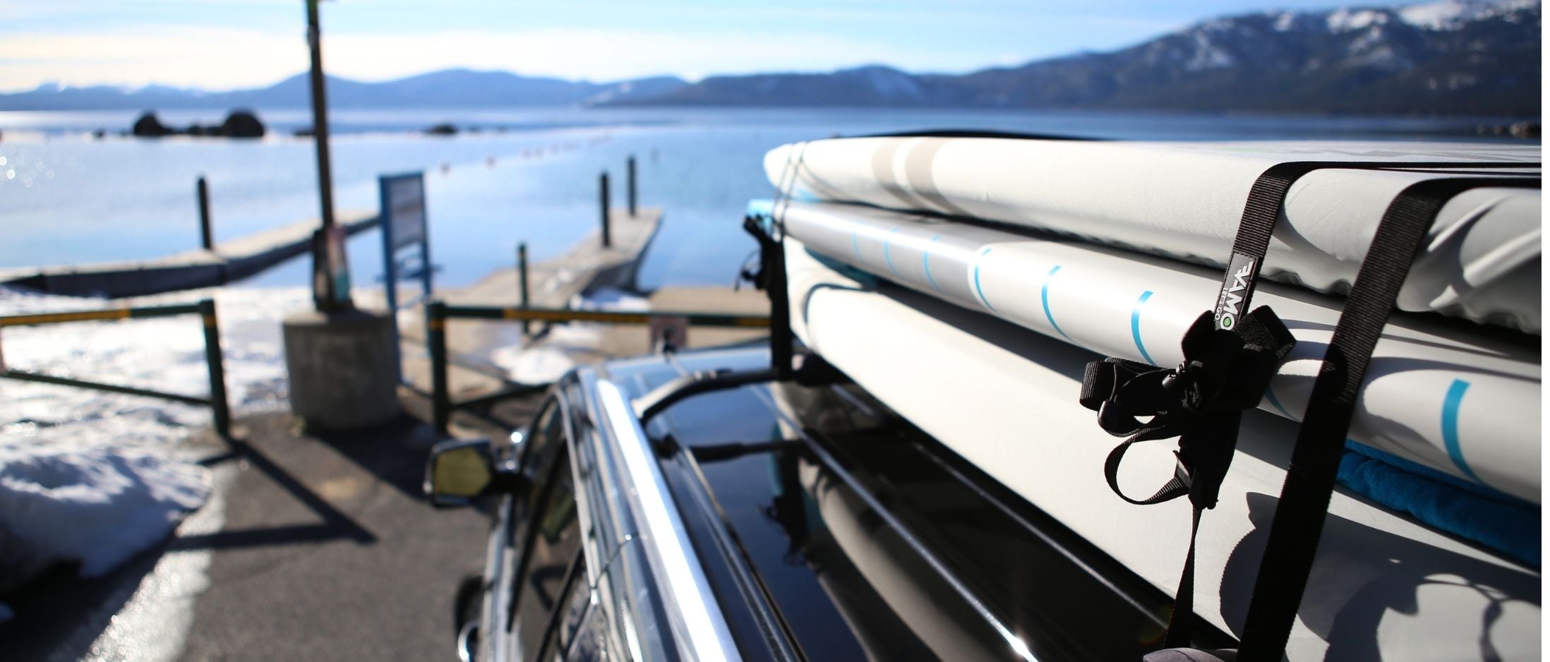 VAMO Rack pads with UV covers on boards, VAMO Tie Downs and a lake in the background. 